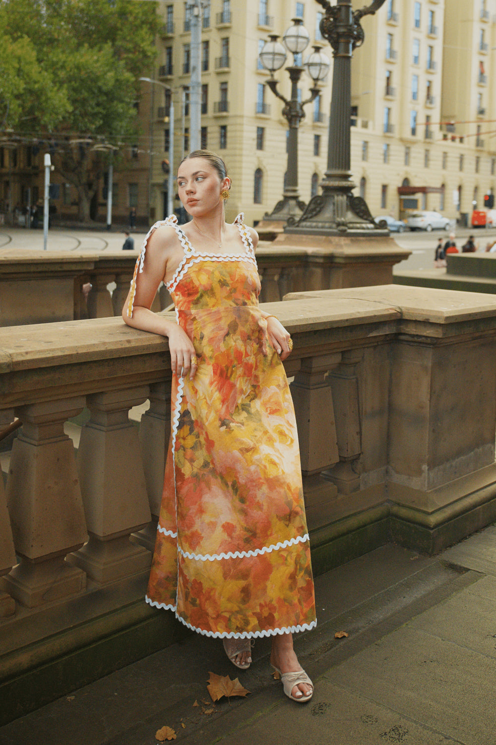 Woman wearing a yellow floral print sleeveless maxi dress with contrast trim from Thr3letter premium women's western wear collection.