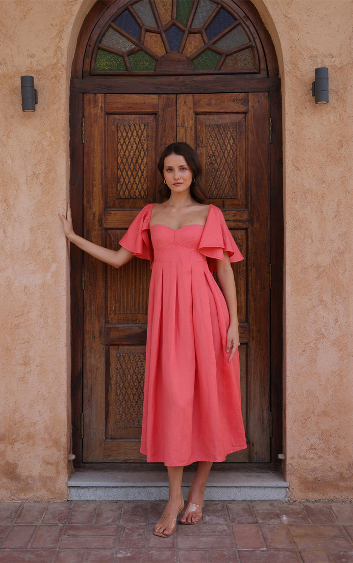 Thr3letter's Seraphina Dress in vibrant salmon pink, featuring a sweetheart neckline and flutter sleeves.