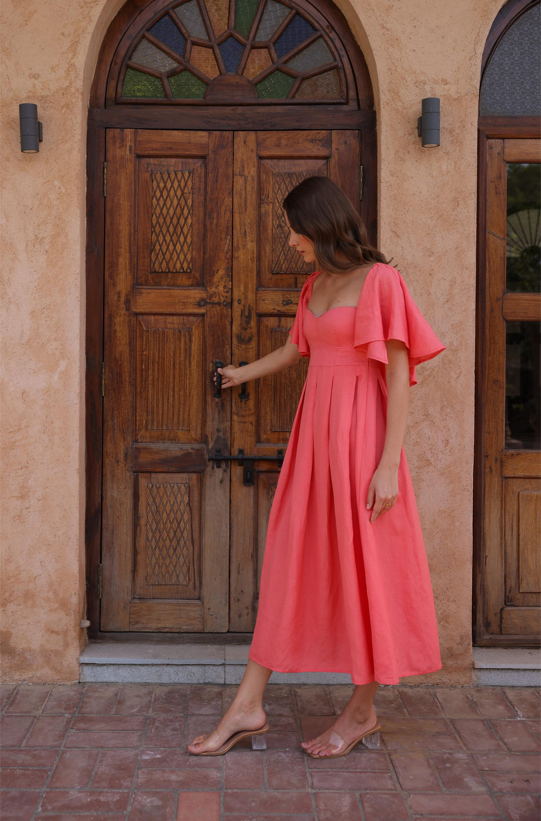 Thr3letter's linen-blend Seraphina Dress in a beautiful salmon color, accentuating the model's graceful pose.