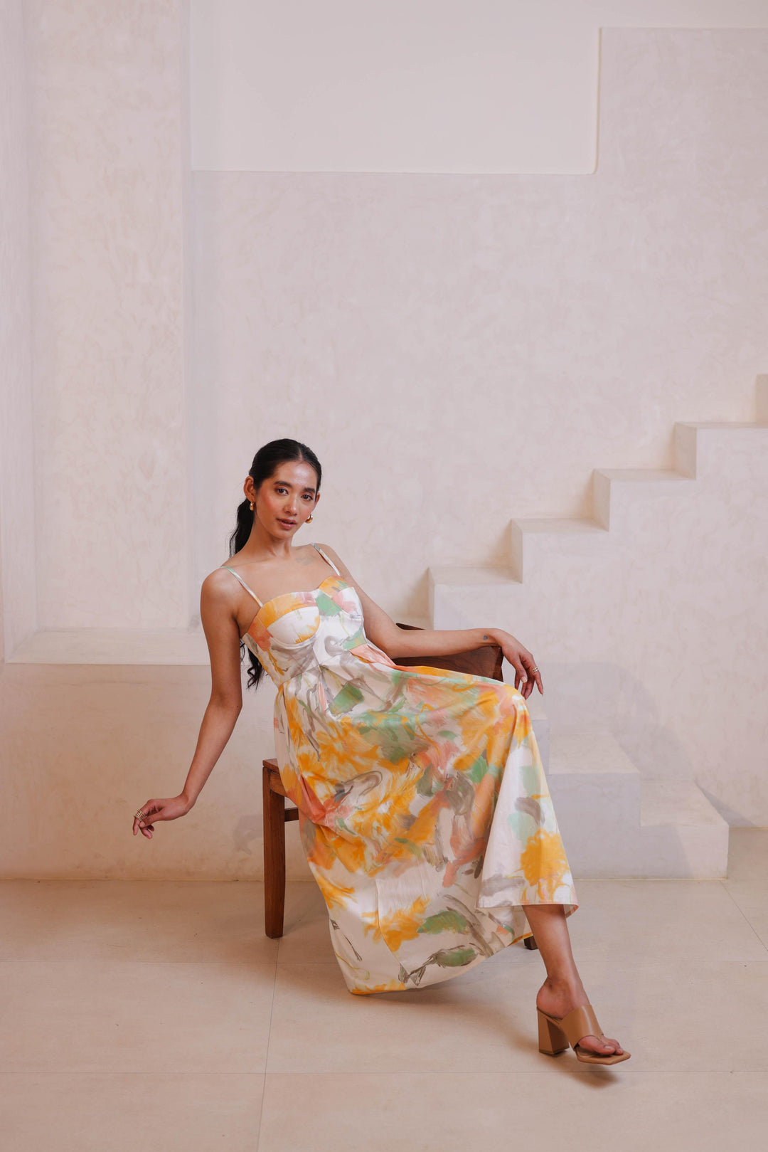 A woman wears the Bahaar Padded Dress from Thr3letter, a vibrant floral print on a silk-cotton base.